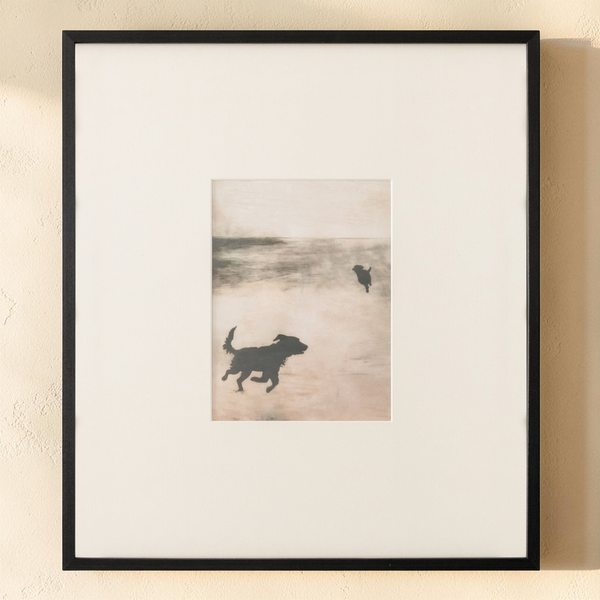 deKor Strand 2 framed print featuring silhouettes of dogs on a misty beach with earthy tones and a black wood frame