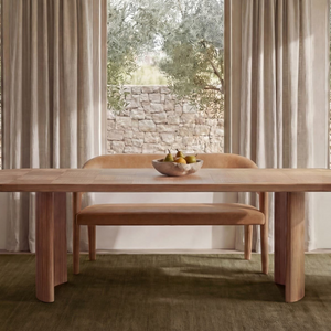 deKor tan top-grain leather barrel back dining bench and matching chairs in a bright, modern dining room setting.