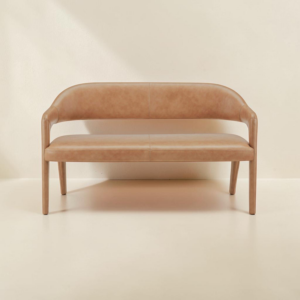 deKor tan top-grain leather barrel back dining bench with a curved iron frame and plush foam seating