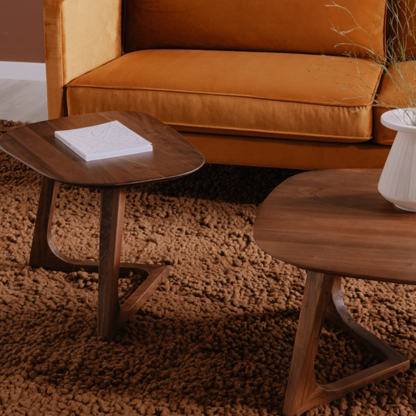 deKor walnut end table with a midcentury modern design, featuring a smooth wooden surface on a textured brown rug.