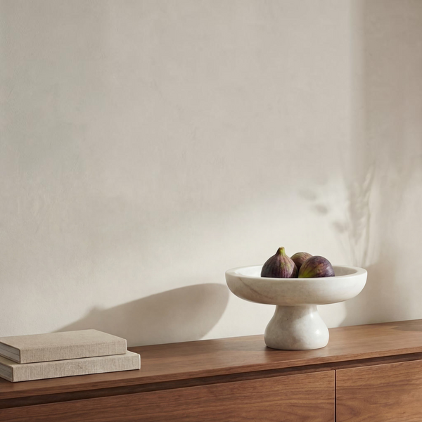 deKor white Rajnagar marble pedestal bowl holding fresh figs on a wooden console table with stacked books