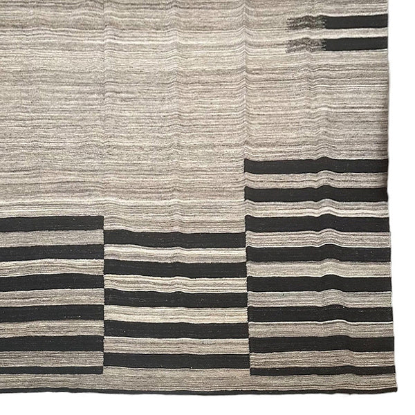 Beige & brown handwoven kilim rug with black stripes in certain areas.