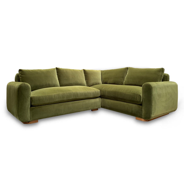 Green velvet sectional sofa with curved wood plinth base
