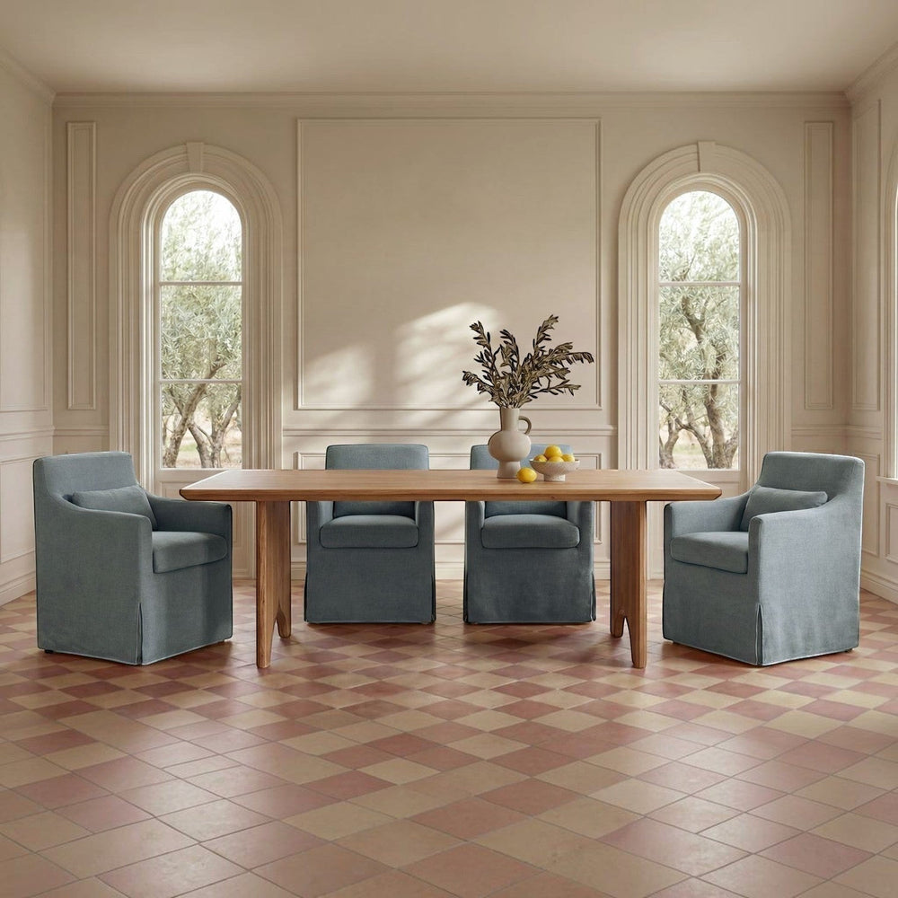 deKor blue slipcovered dining chair with curved arms, inverted pleats, and a matching lumbar pillow.